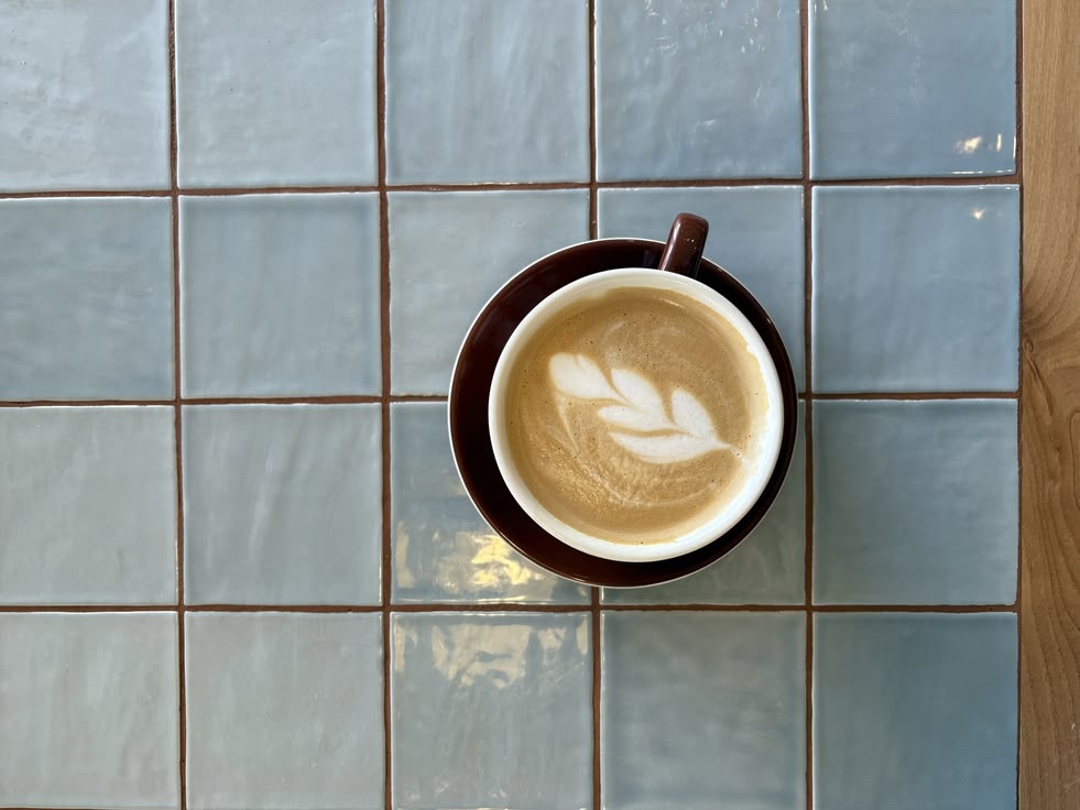 Flat White mit Latte Art auf blauen Fliesen