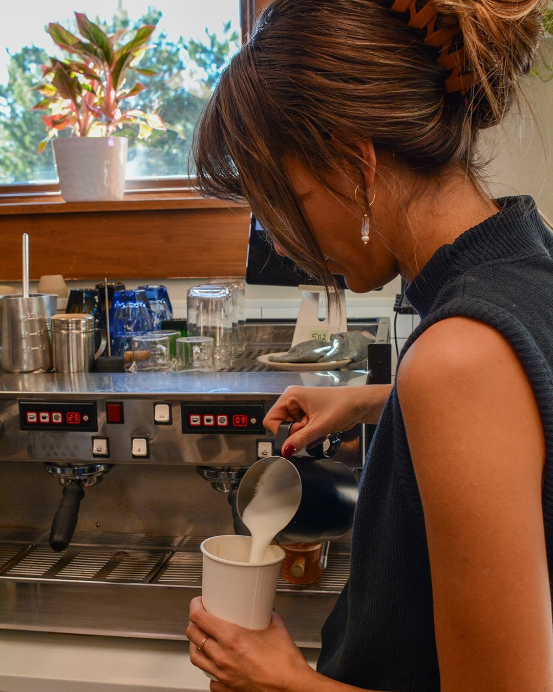 Lou schenkt Milch bei der Espressomaschine in einen Becher