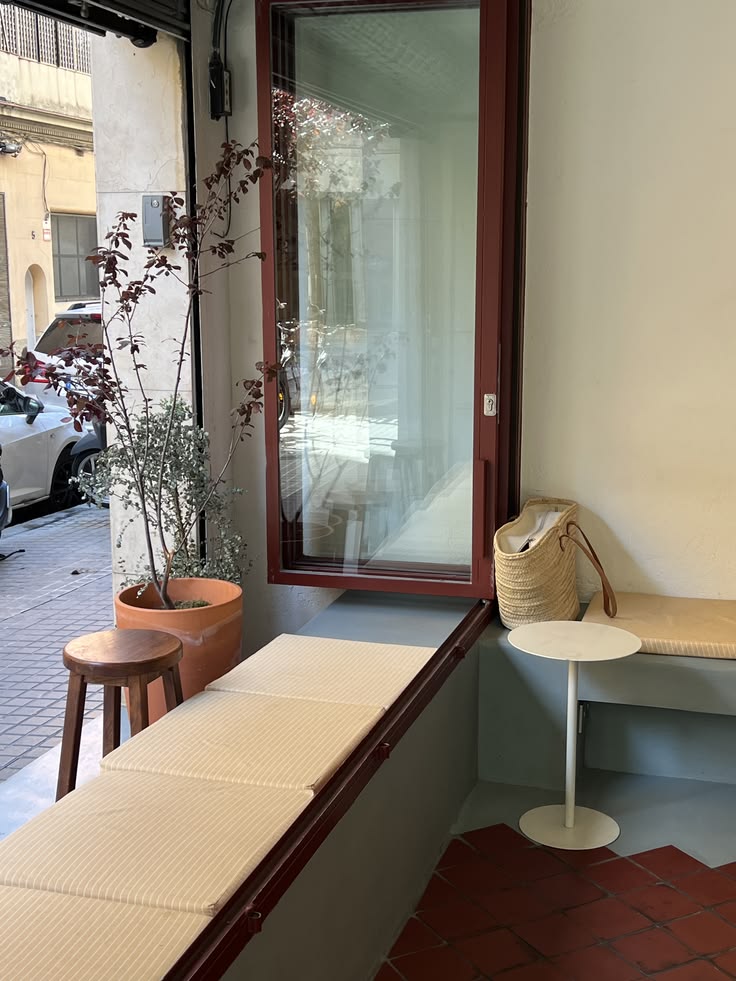 Sitzbank am Fenster mit Kissen, Holzhocker und Pflanze