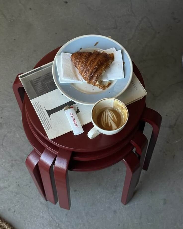 Croissant und Cappuccino auf einem roten Hocker